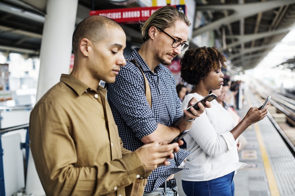 tr&ecirc;s pessoas em uma fila, com olhos voltados para os seus smartphones - foto pixabay