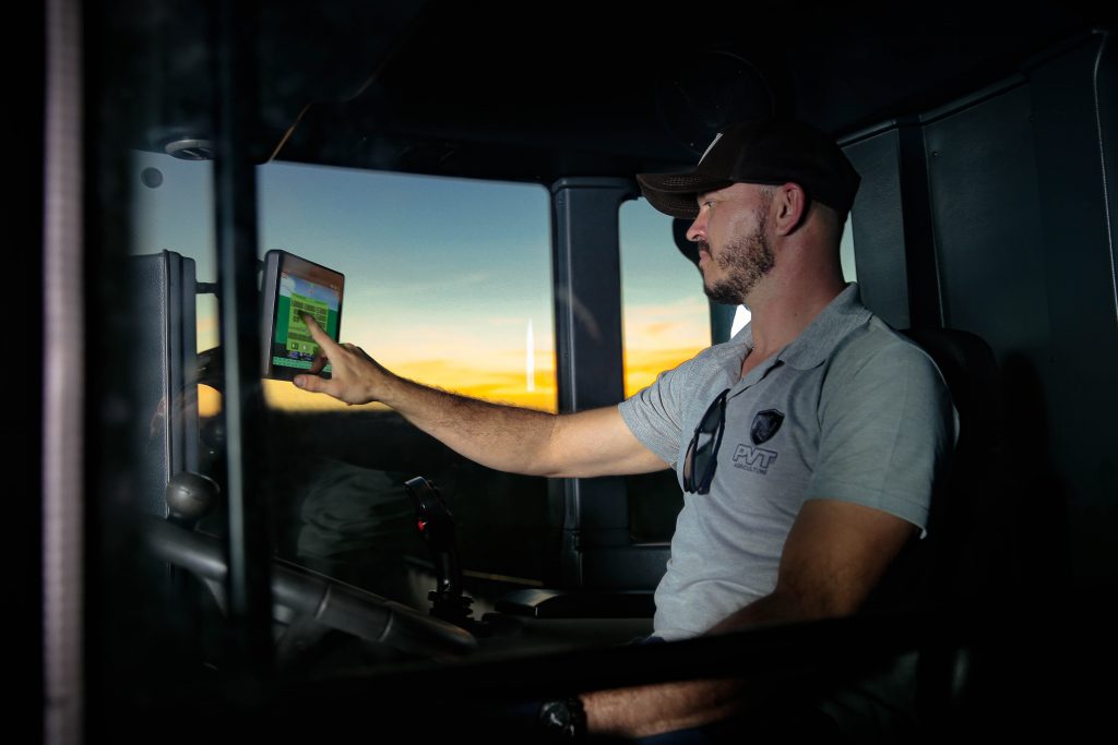 homem dirigindo m&aacute;quina agr&iacute;cola consulta tela de minicomputador 
potencial do agroneg&oacute;cio

