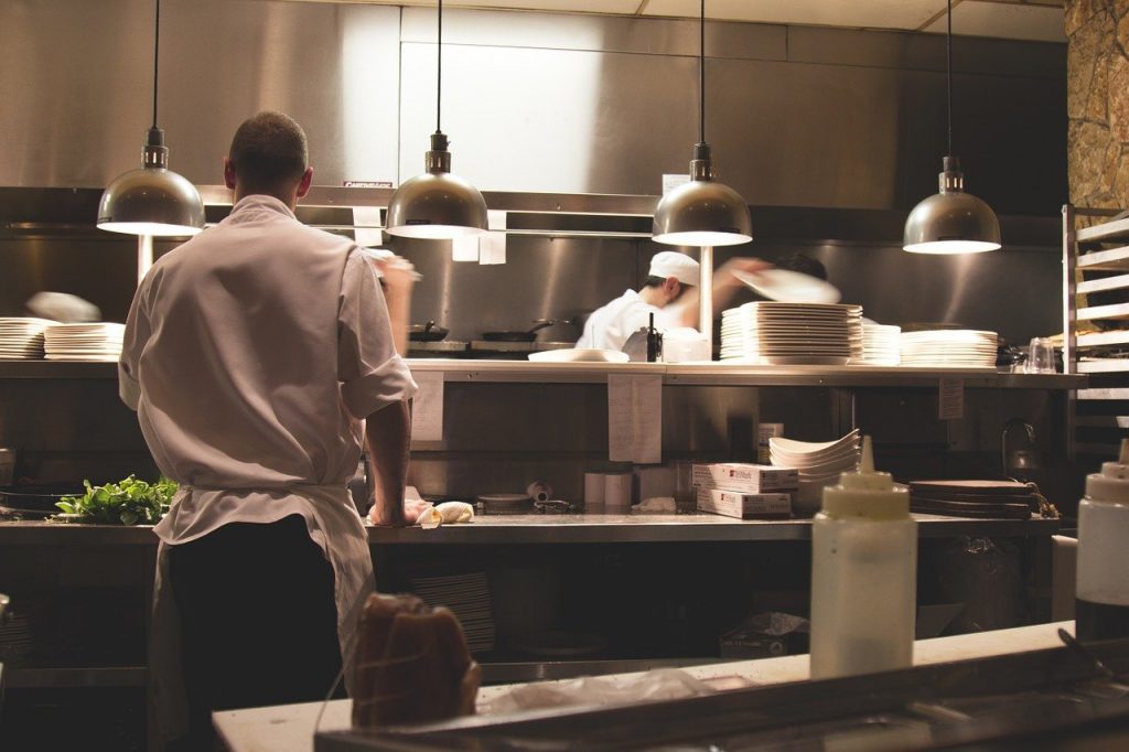 food service - foto de uma cozinha de restaurante com tr&ecirc;s cozinheiros em atividade 
foto: pixabay