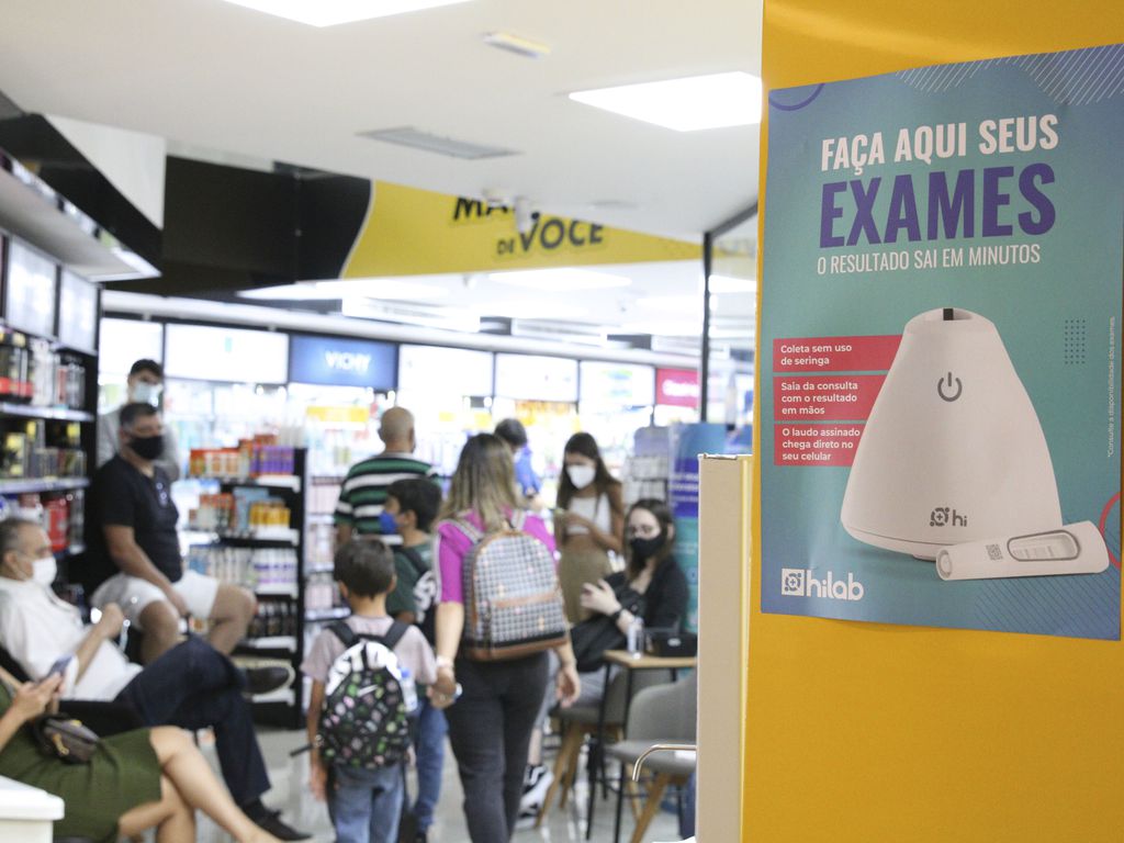 notas econ&ocirc;micas: foto Ag&ecirc;ncia P&uacute;blica
aglomera&ccedil;&atilde;o de pessoas em farm&aacute;cia para exames de gripe. Em destaque, um cartaz anuncia fa&ccedil;a aqui os seus exames