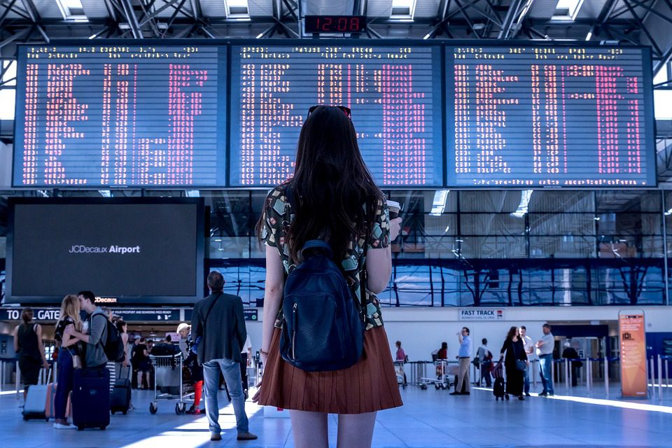 Mulher com mala diante de painel de voos de aeroporto- foto: Pixabay