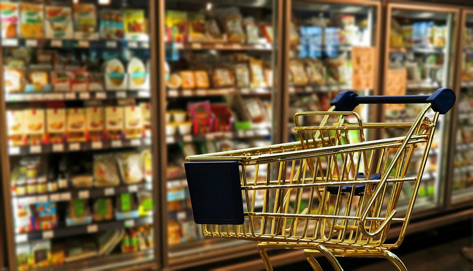 Interior de supermercado com destaque para um carrinho de compras. Imagem: Pixabay